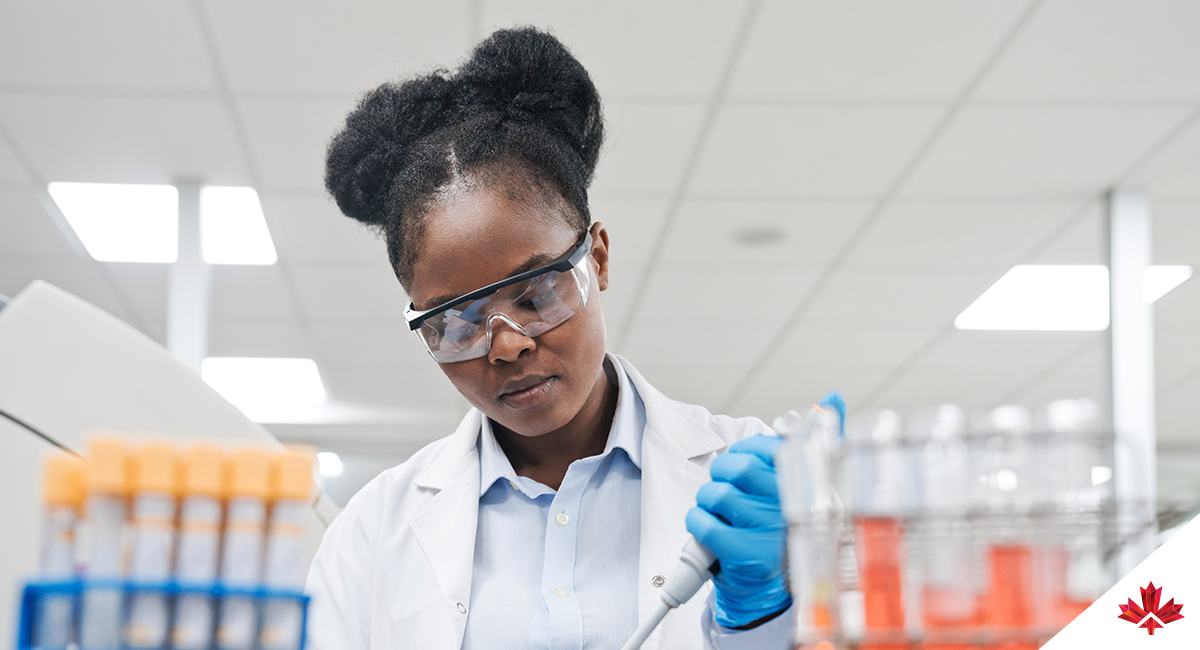 Jeune femme scientifique remplissant un produit chimique à l'aide d'une pipette lors d'un travail en laboratoire.